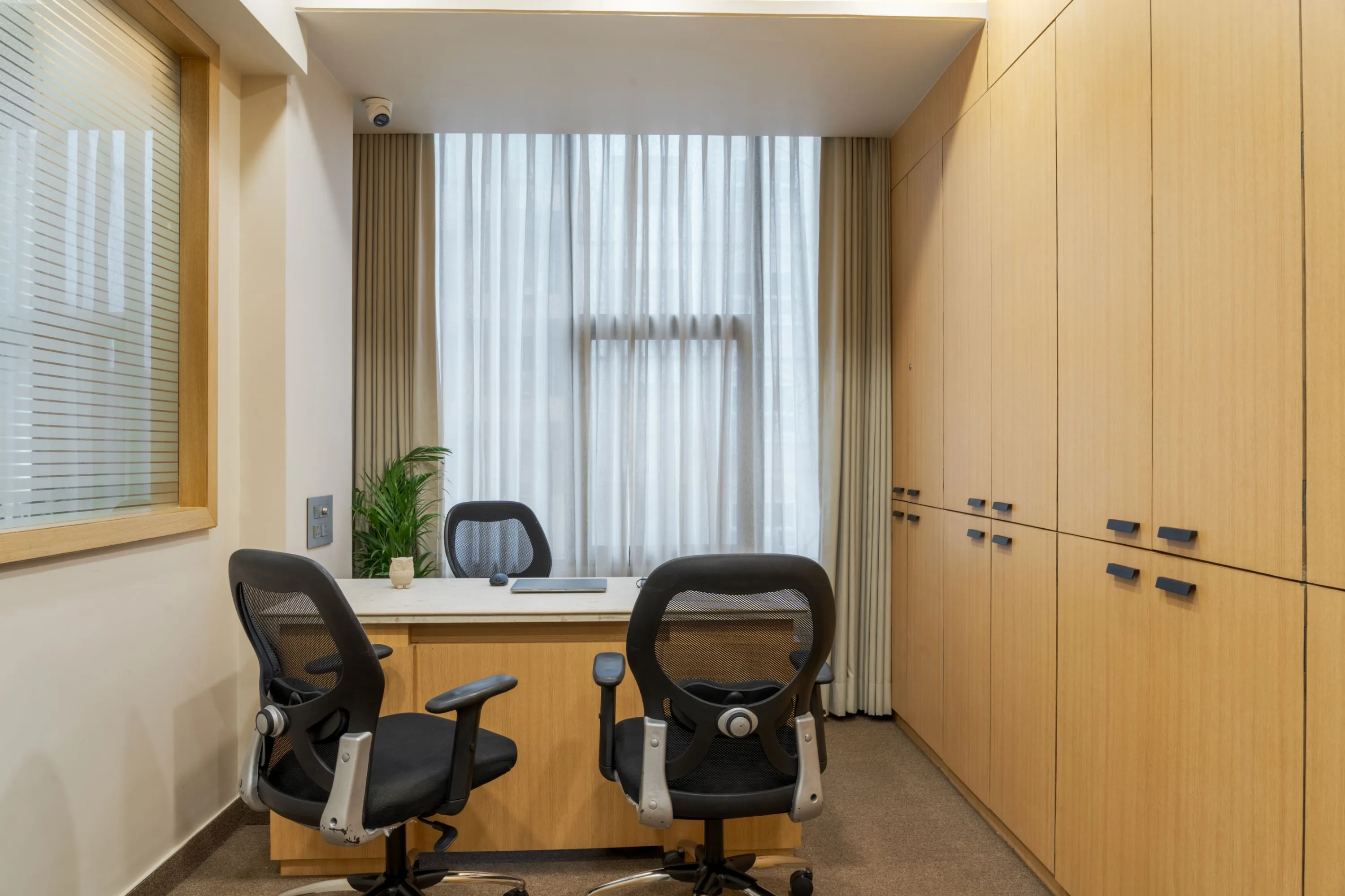Small meeting room with two mesh chairs against a wood cabinet wall