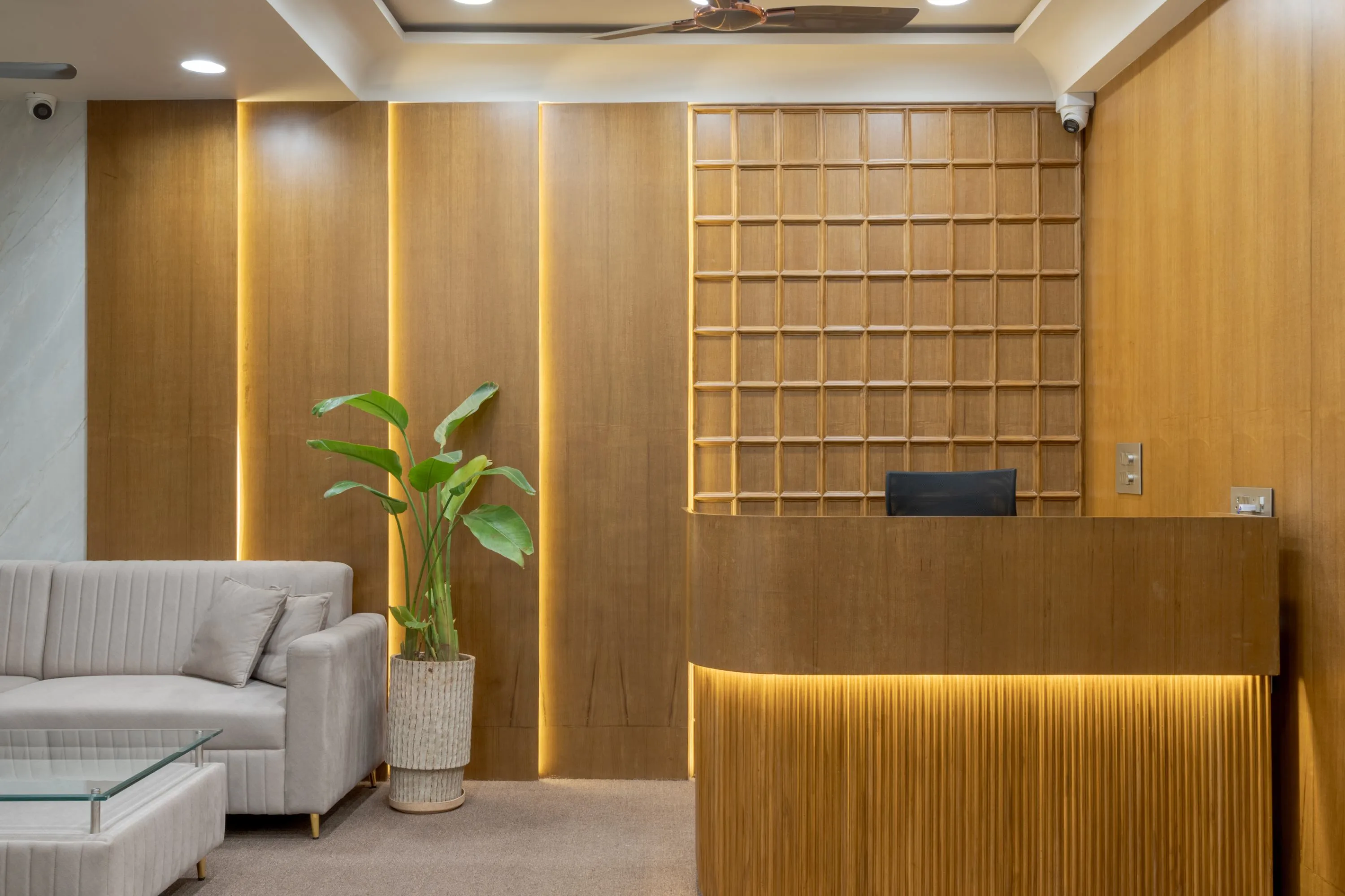 Reception desk in fluted timber, backed by a square wooden lattice wall