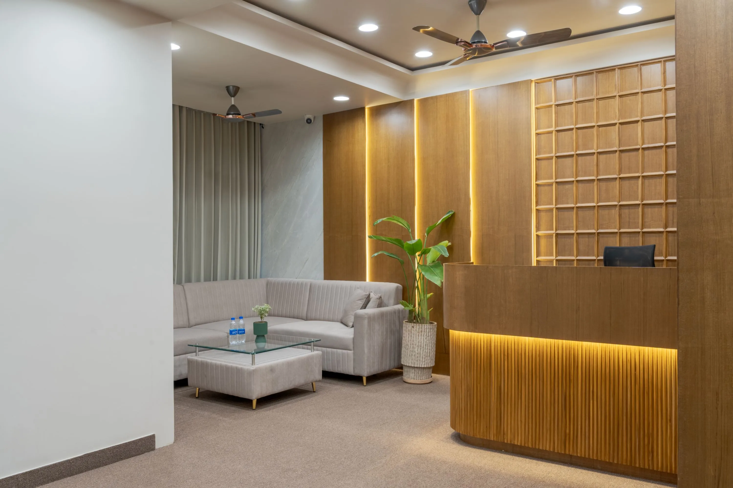 Reception lounge with a sectional sofa and the fluted reception desk beyond