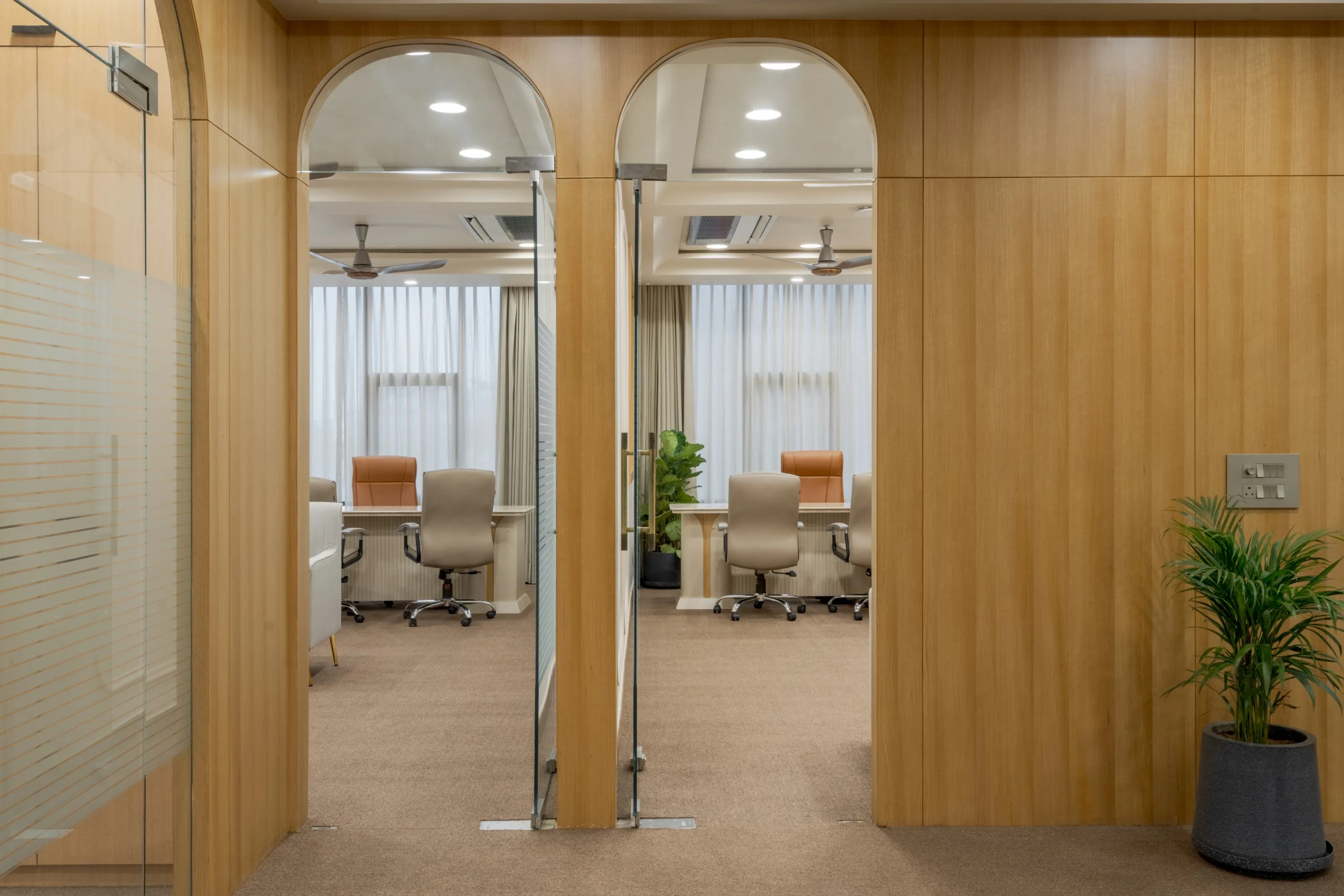 Corridor of arched glazed doors opening onto glass-walled cabins