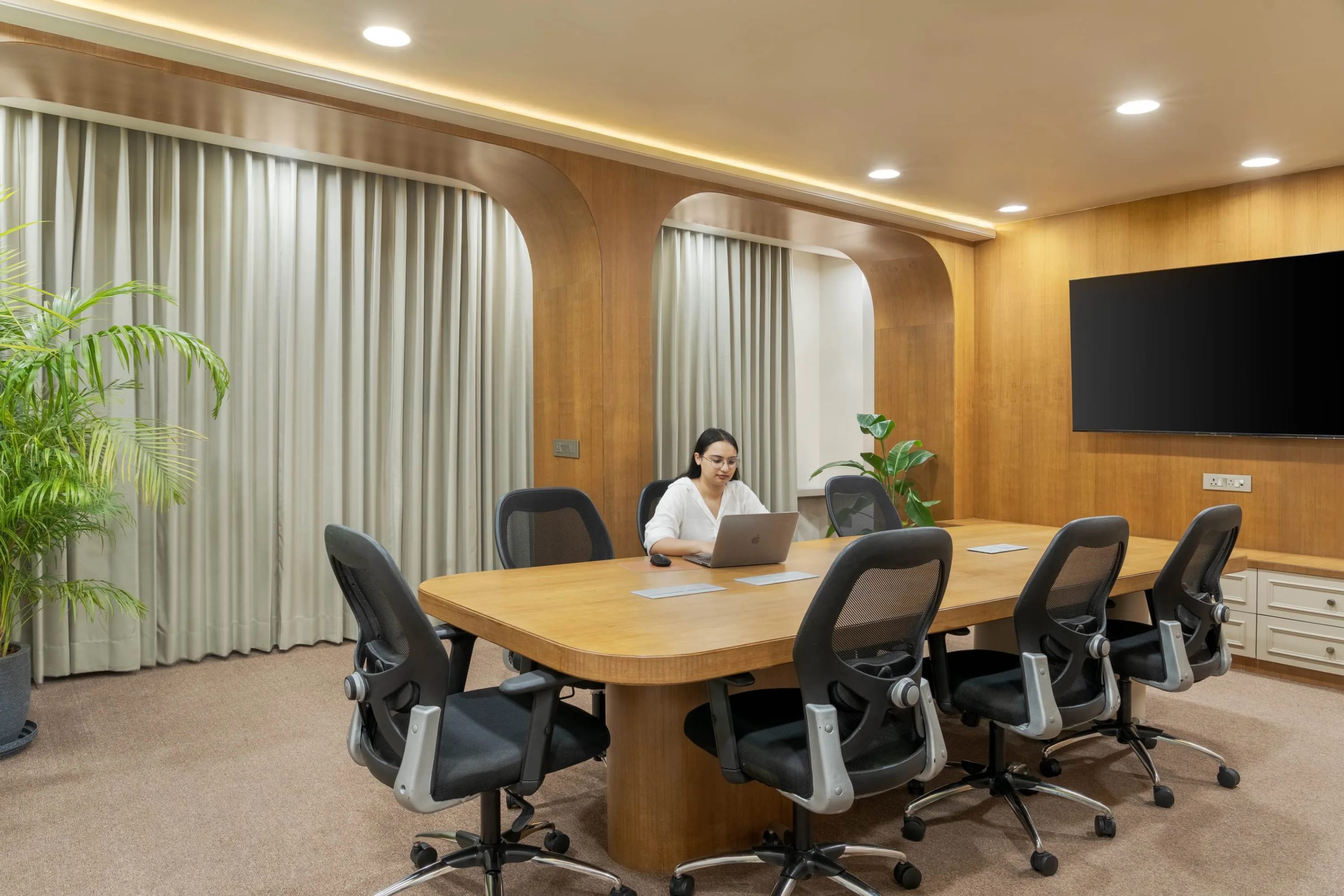 Boardroom table with recessed arched panelling and a wall-mounted screen