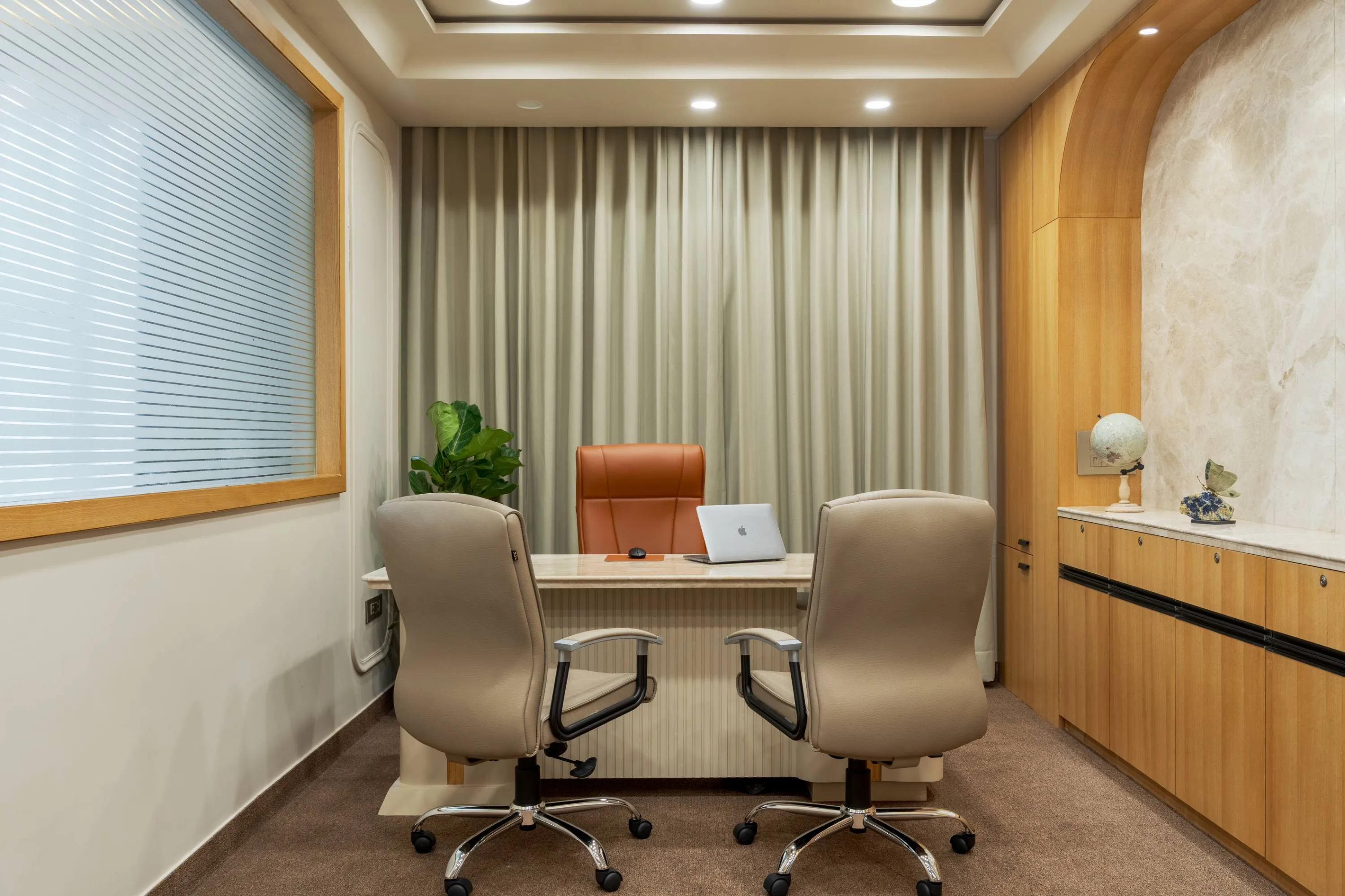 Director's desk in travertine marble, facing a wood-panelled cabin with curtained windows