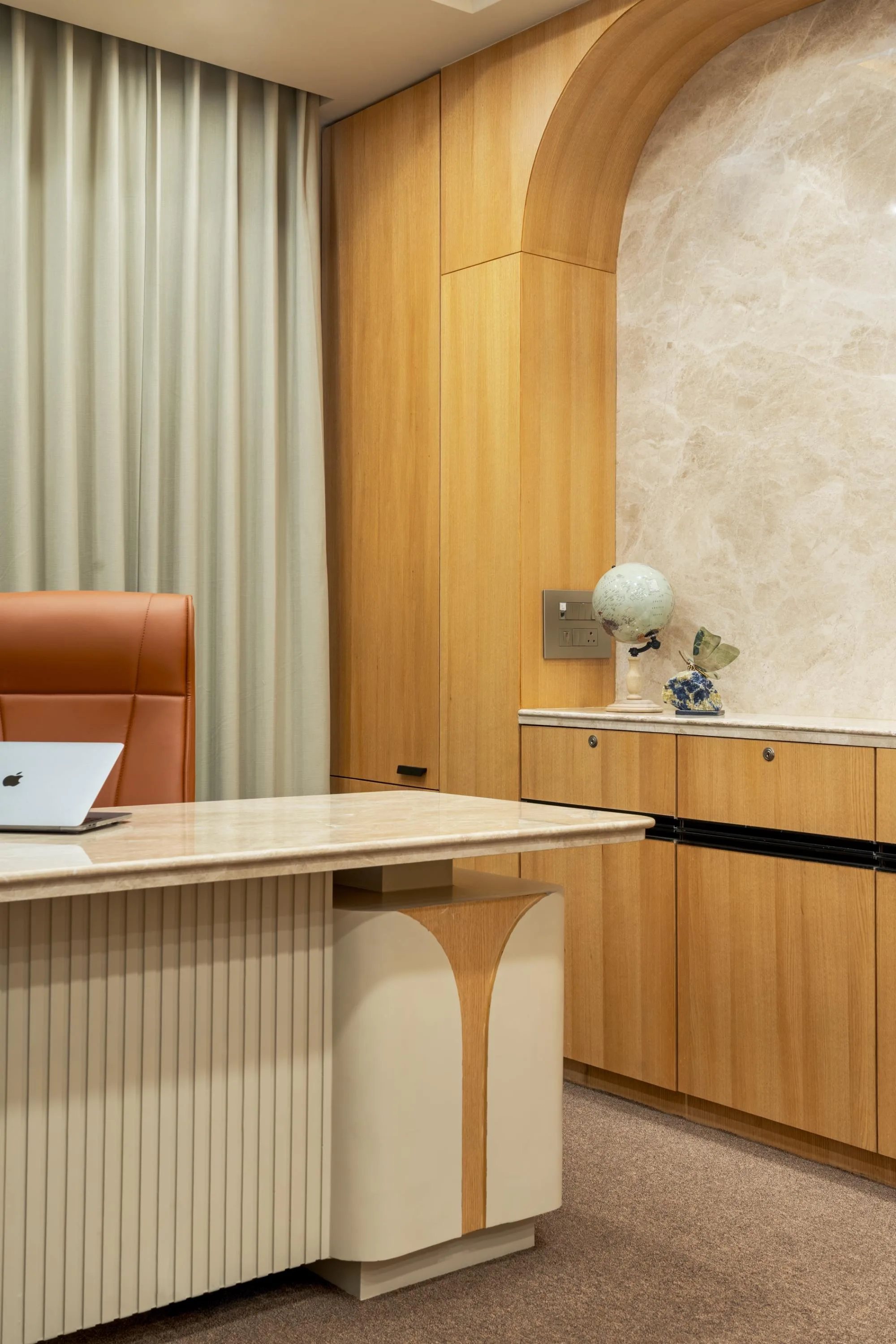 Waiting lounge with two pale grey sofas beneath a leaf-print wallpaper archway