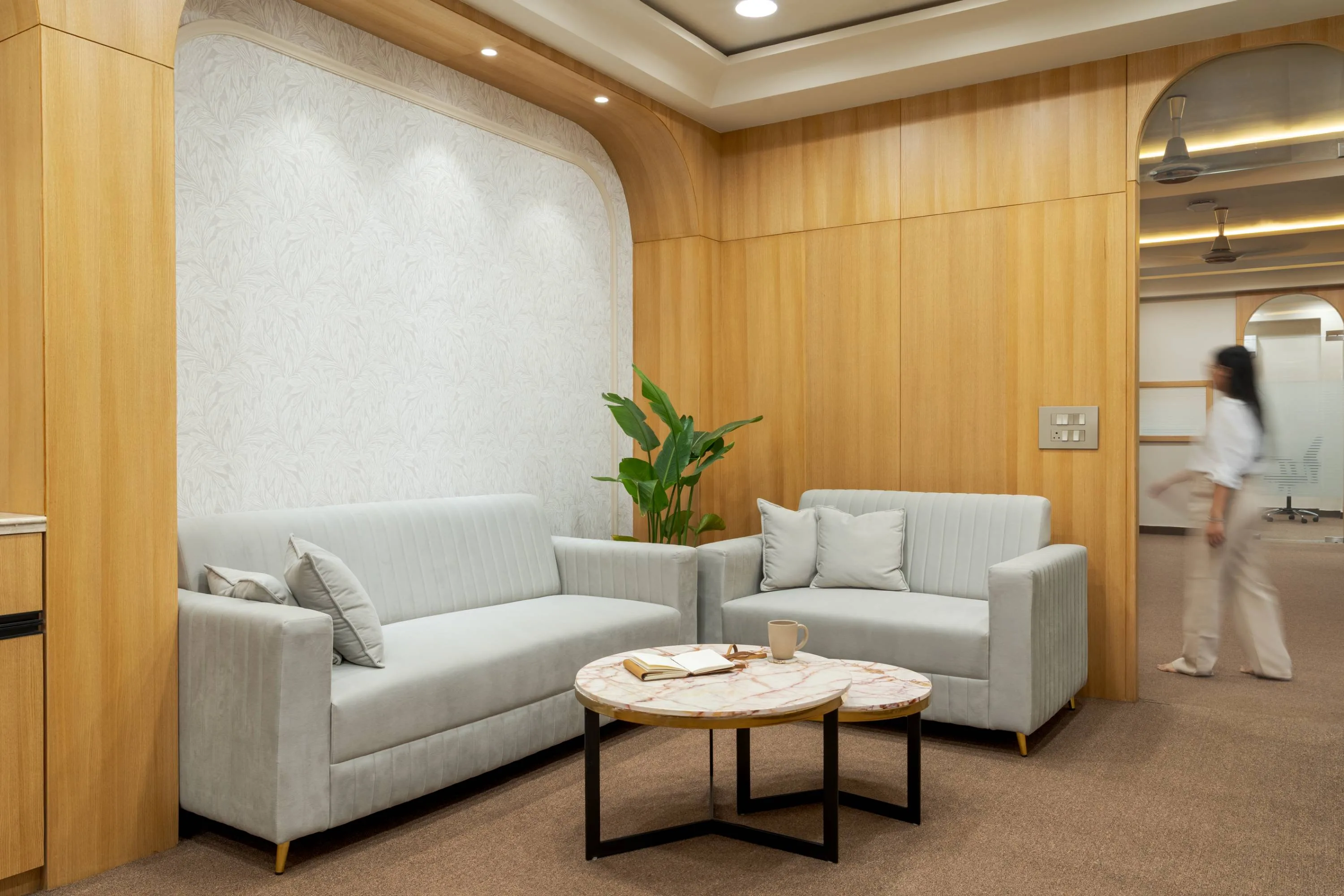 Waiting lounge corridor with a colleague passing between glazed cabins