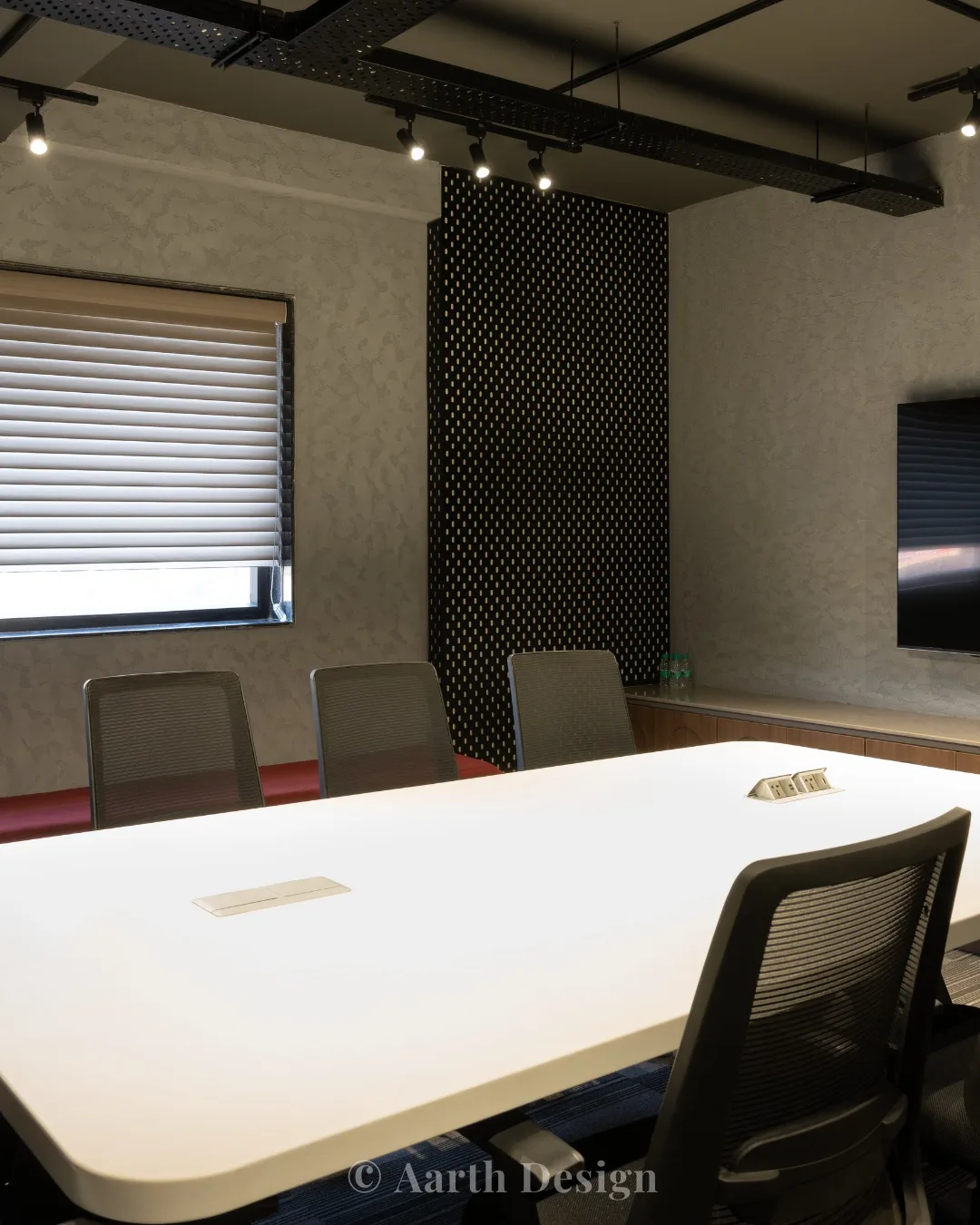 Boardroom with a perforated dark feature wall and a long conference table
