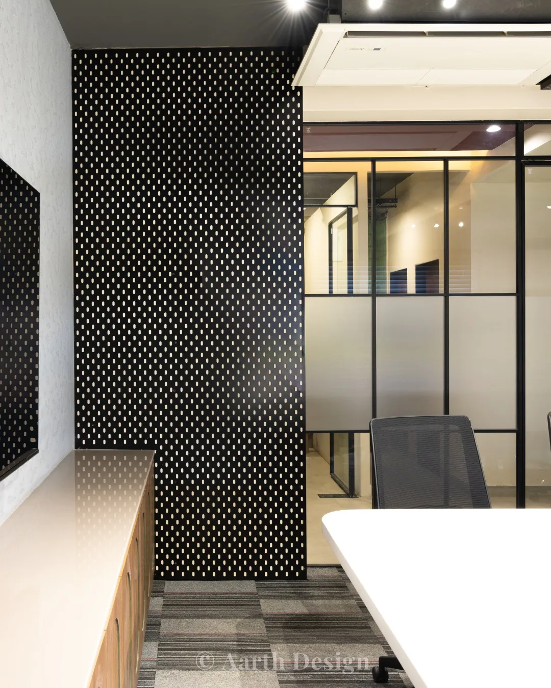 Passage between a perforated dark feature wall and frosted-glass cabins