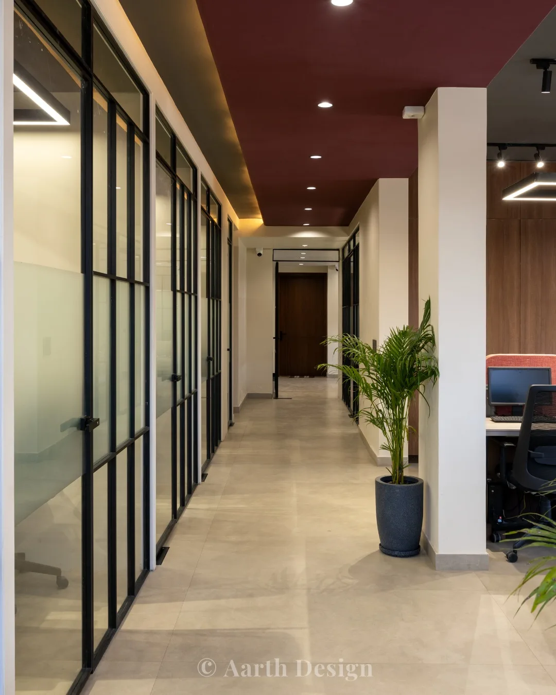 Corridor lined with black-framed glass cabins under a maroon ceiling band