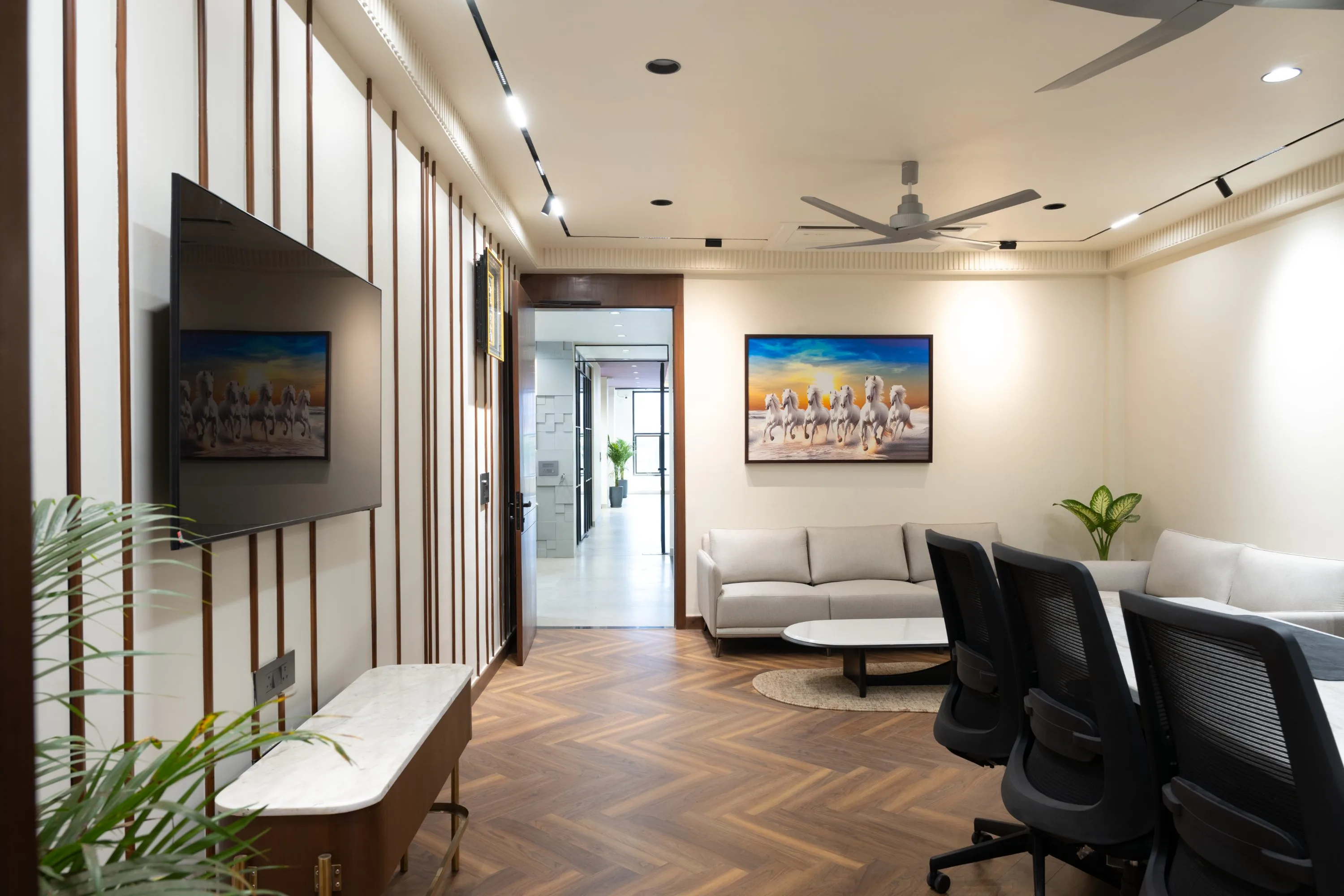 Lounge corner with a herringbone floor, grey sofas and a framed horse painting