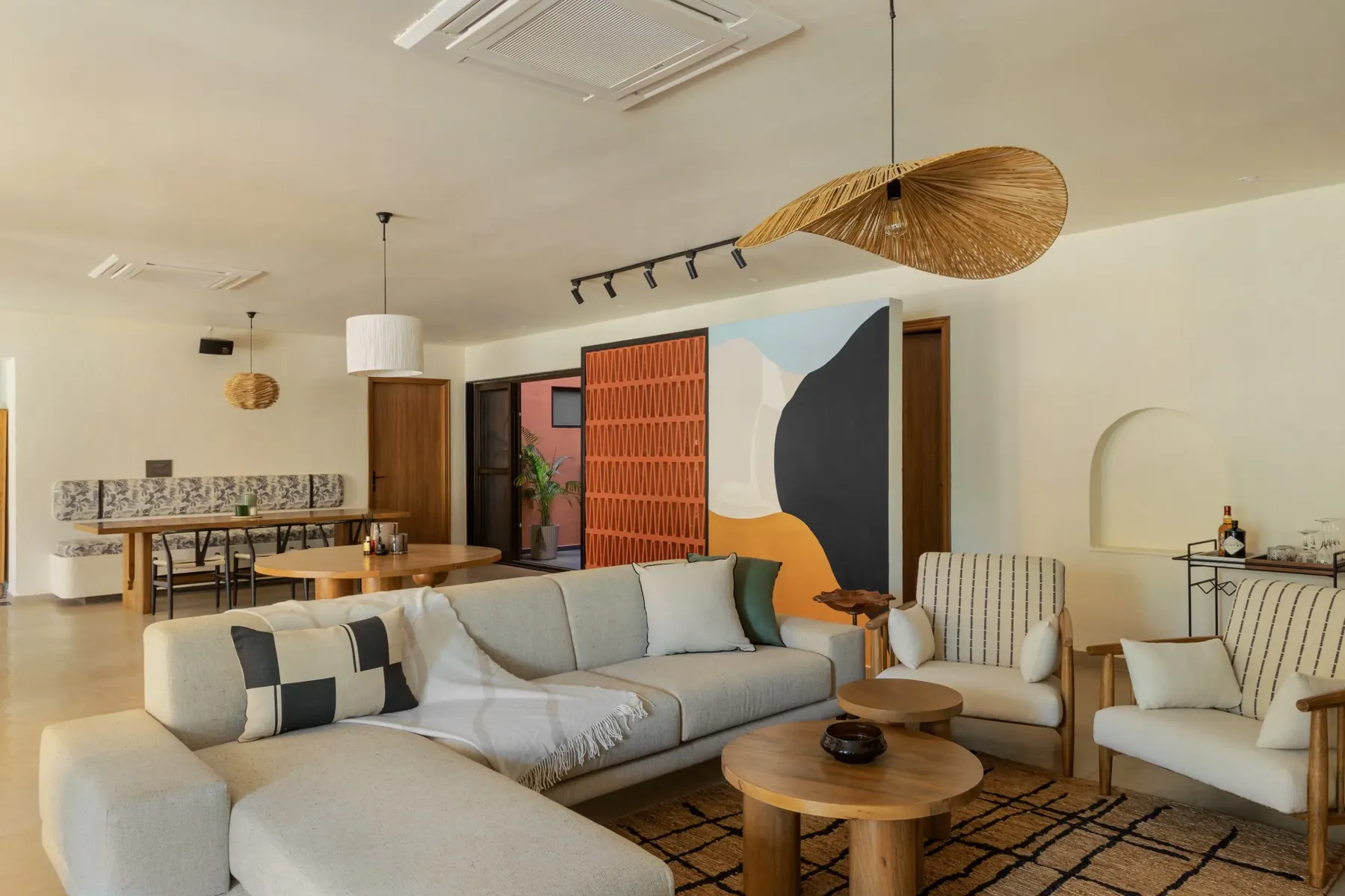 Open living, dining and kitchen under a woven pendant light