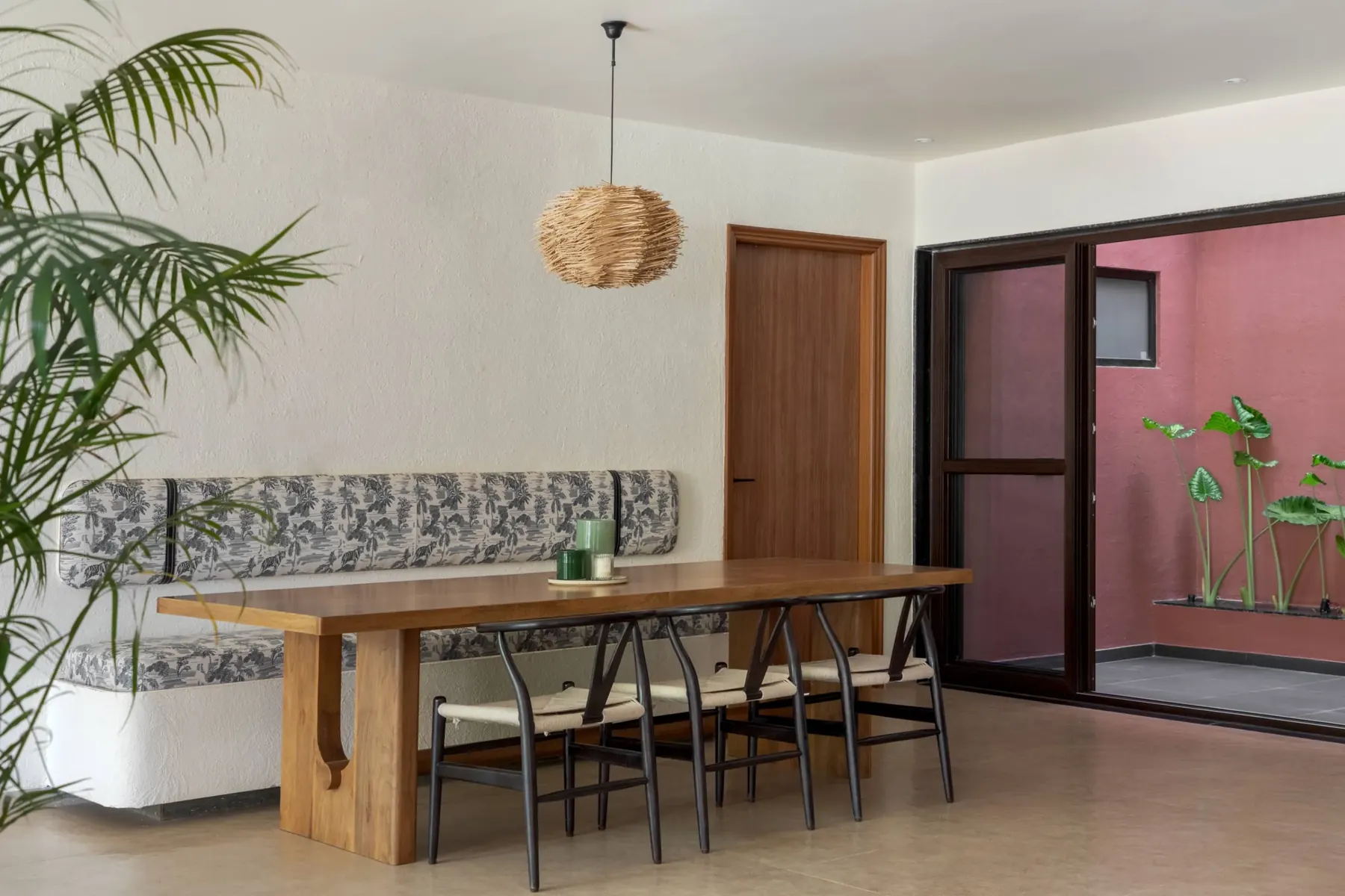 Dining nook with a thatched pendant light and a jaali screen doorway beyond