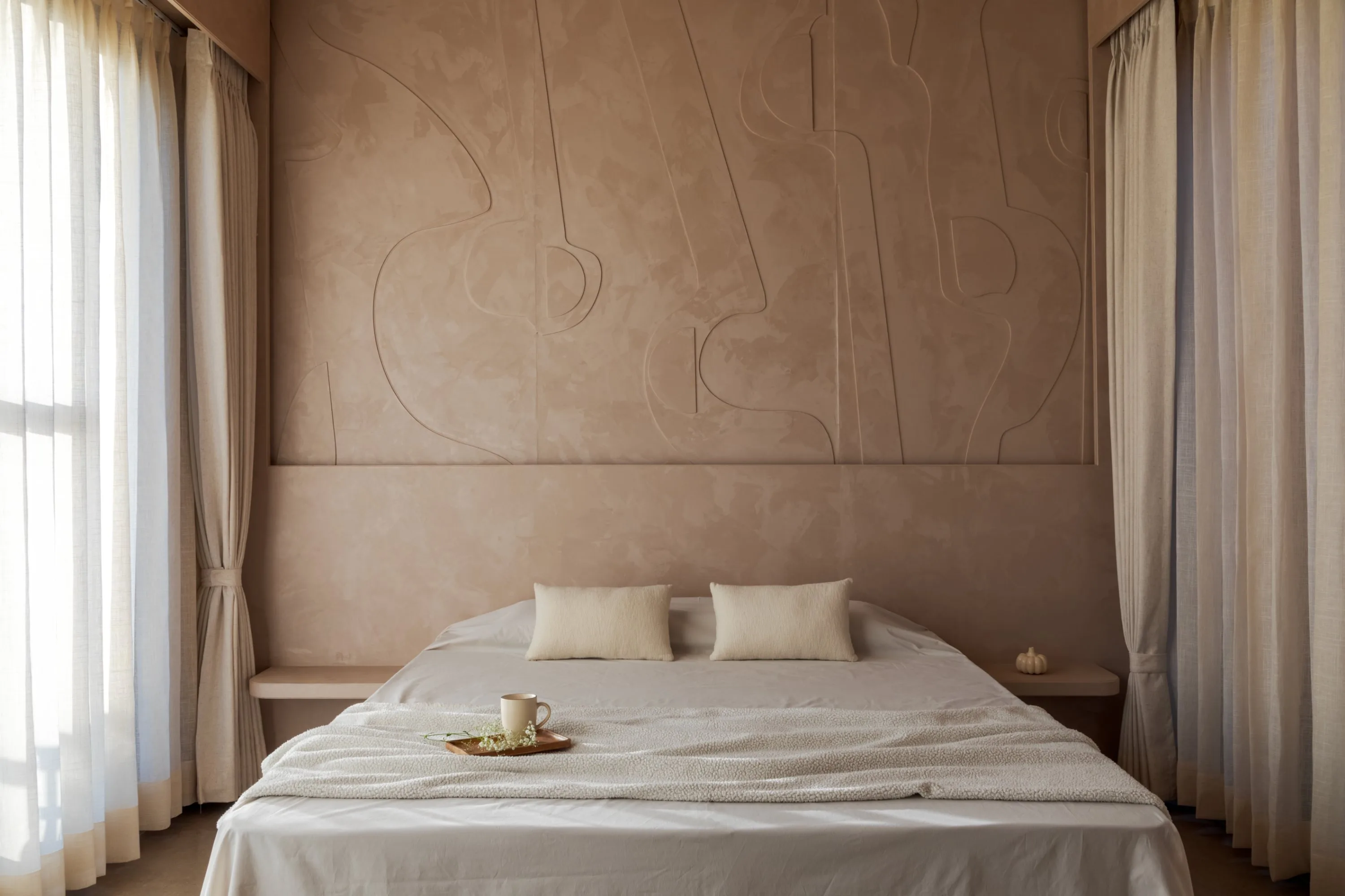 Bedroom with a sculpted plaster relief rising behind a floating console