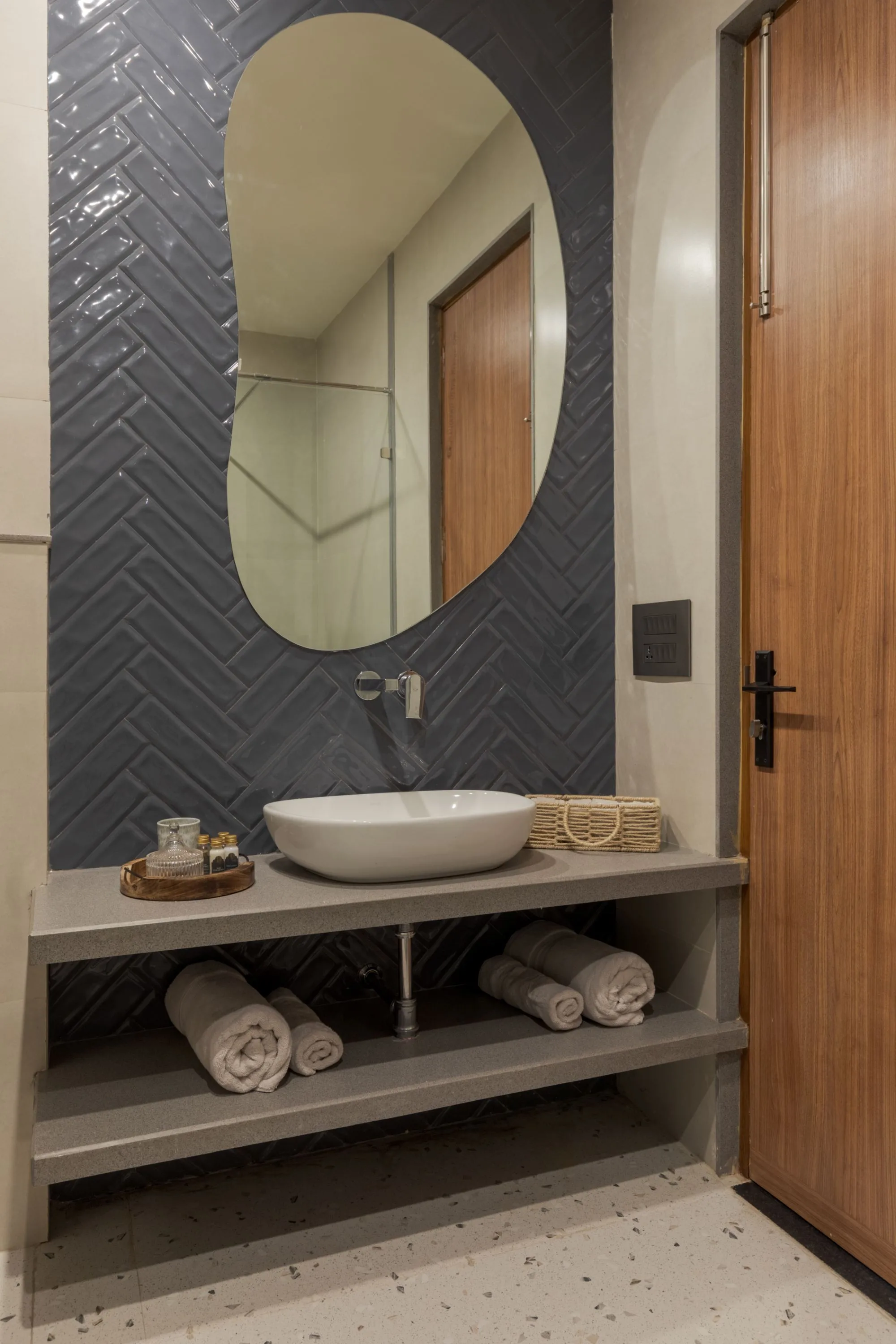 Bathroom in herringbone tile with an organic-shaped mirror