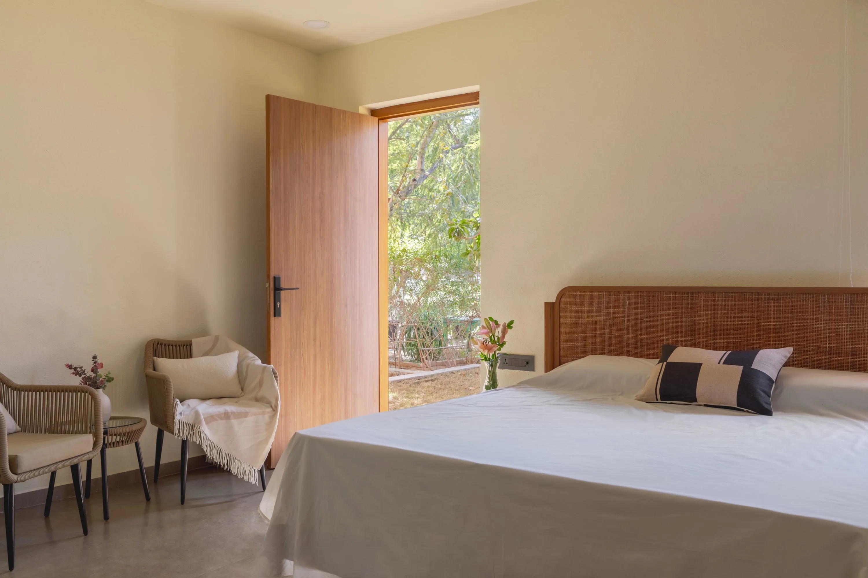 Bedroom with a rattan headboard and a door opening onto the garden