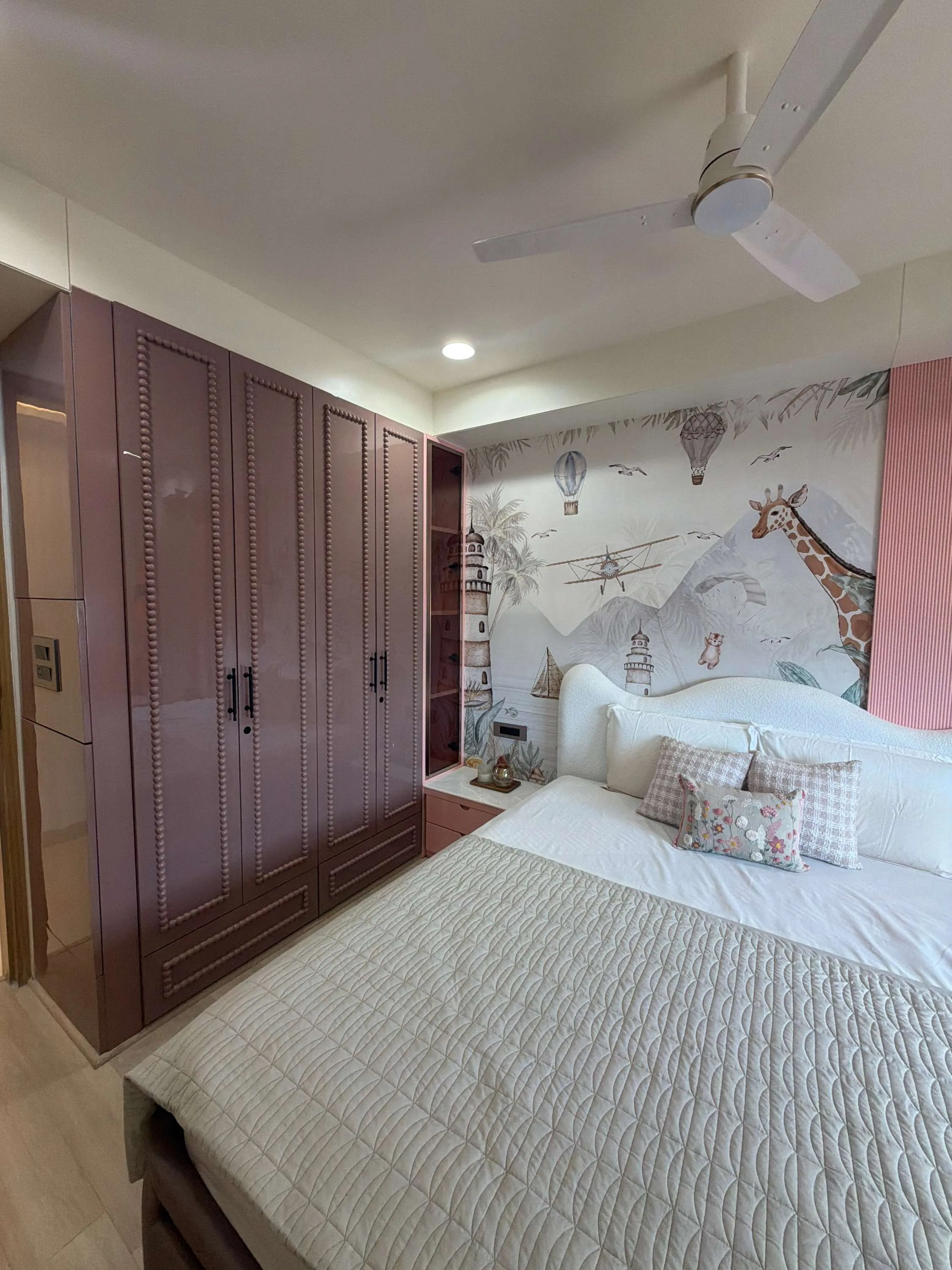 Children's bedroom with a mauve lacquered wardrobe and a mountain-and-balloon mural