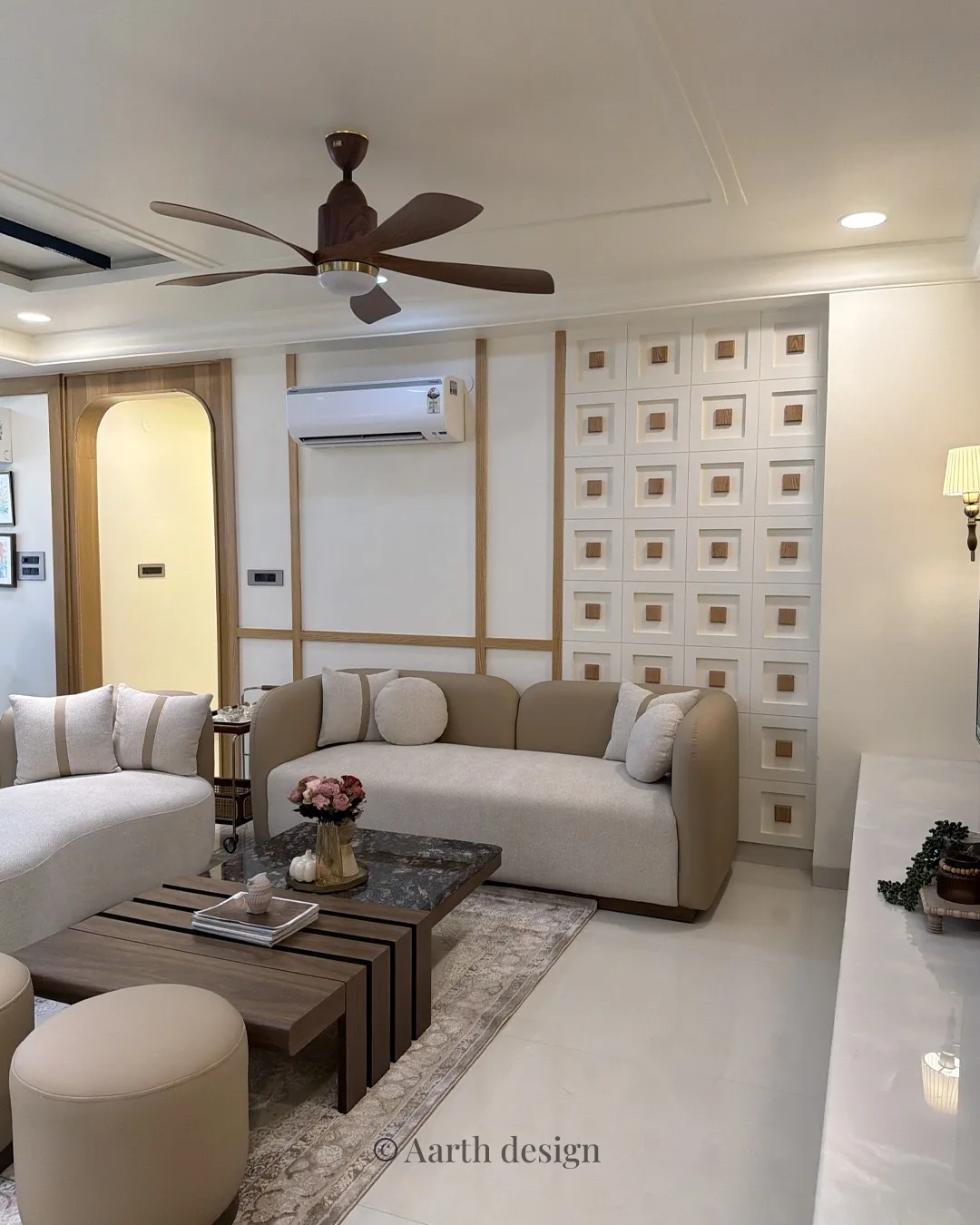 Living room with a cream sofa beneath an arched niche and a grid of square inset panels