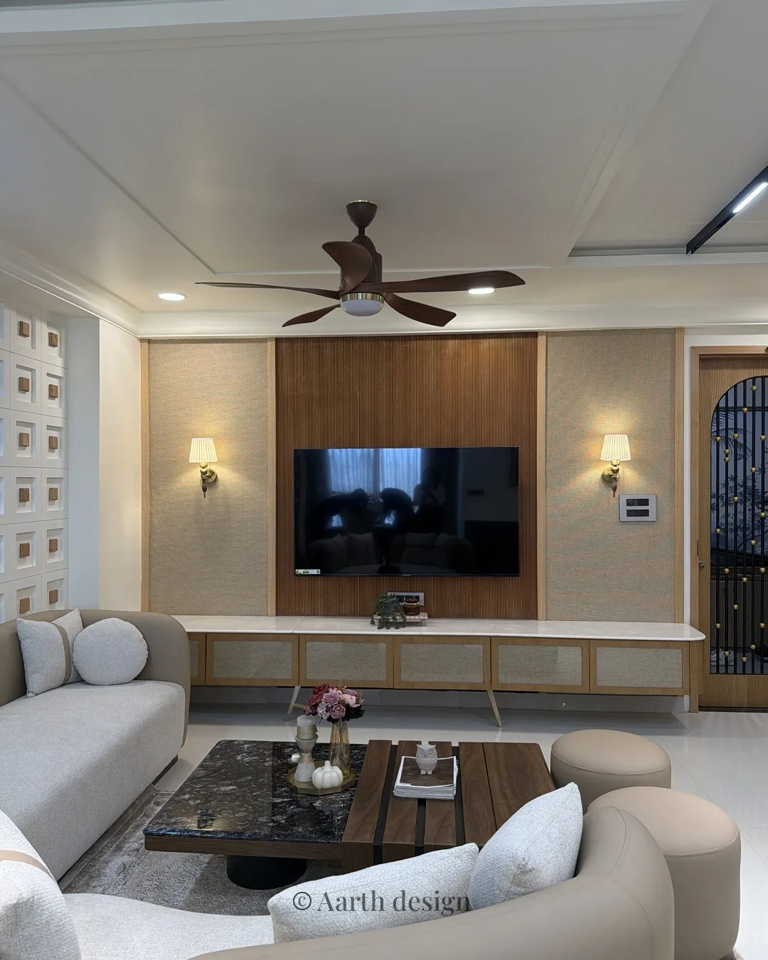 Living room with a fluted media wall, a square-inset feature panel and warm wall sconces