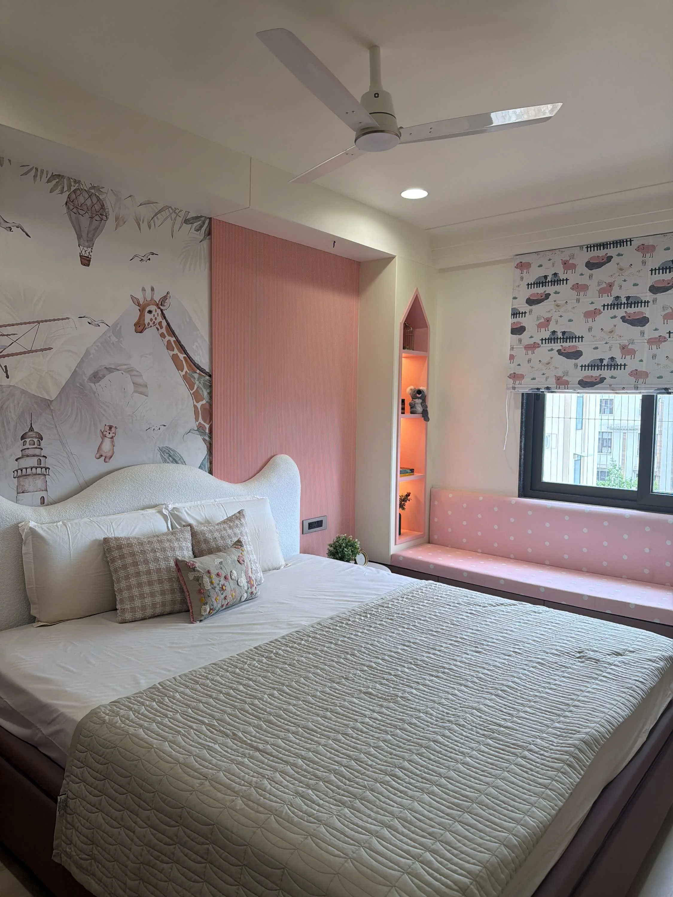 Children's bedroom with a giraffe-and-hot-air-balloon mural and a pink window seat